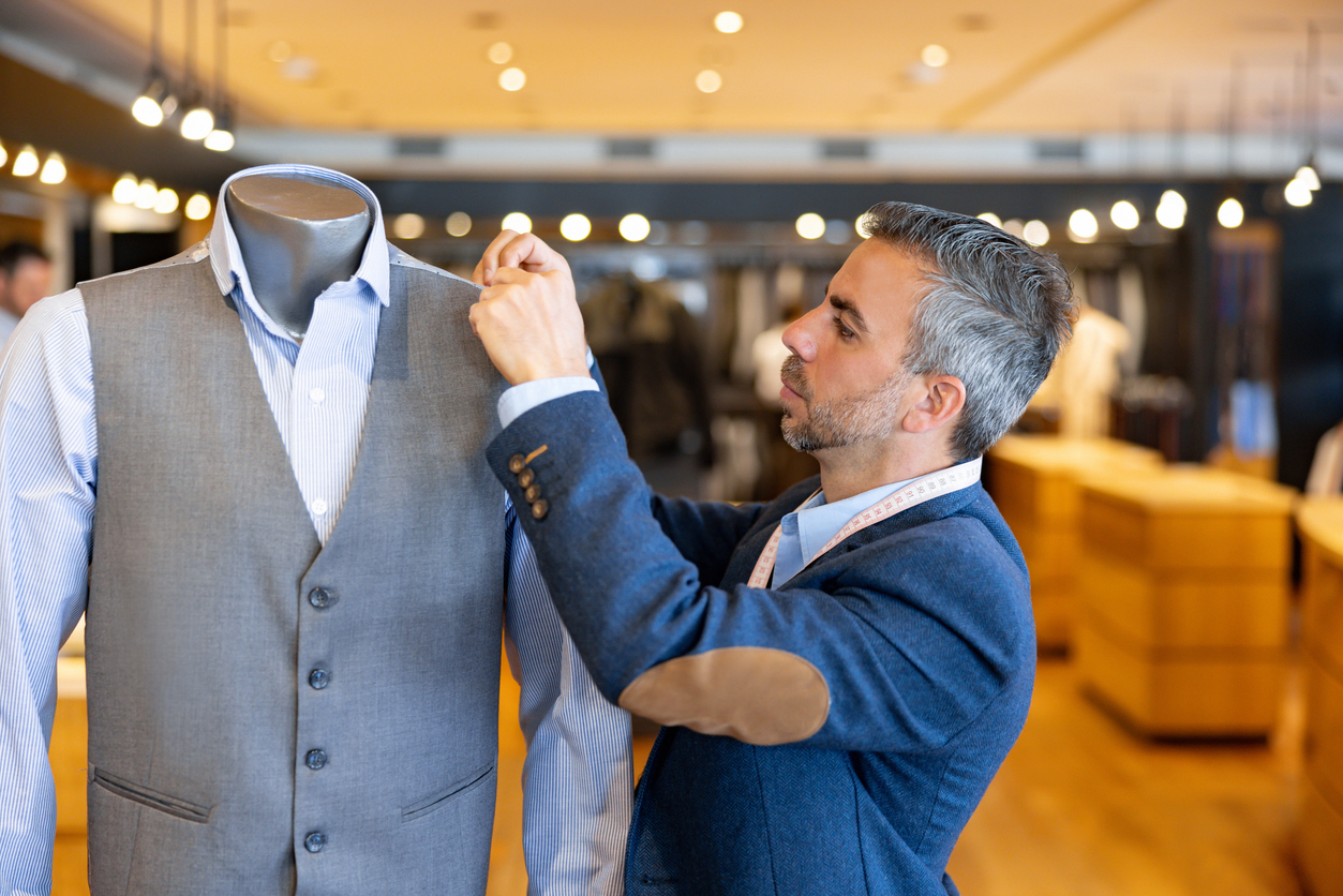Tailor stitching clothes on a mannequin at his shop